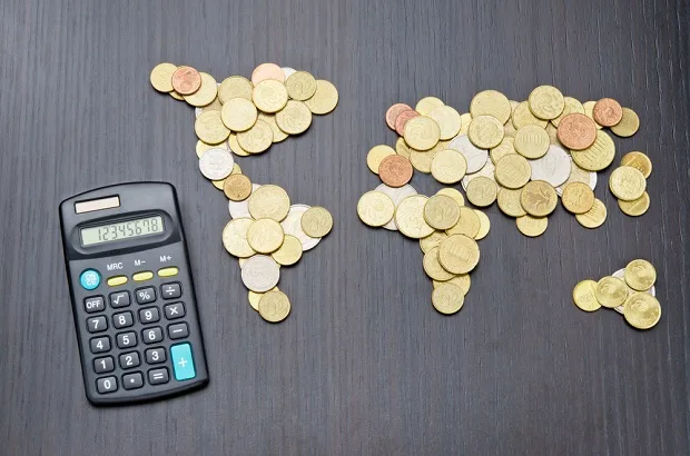 Coins and calculator on a table calculating tax when moving overseas